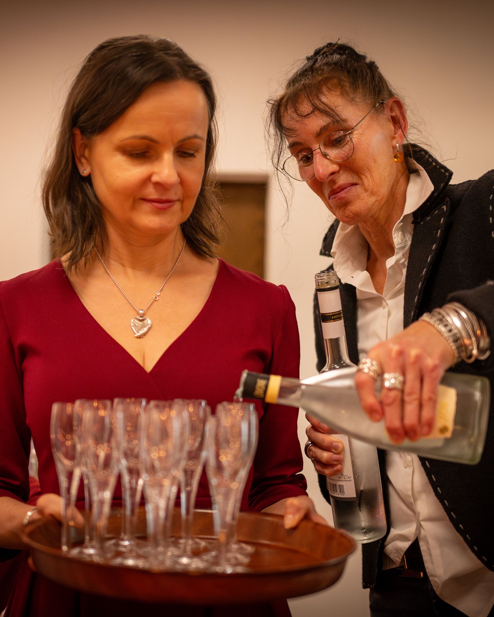 Zwei Frauen schenken bei einer Feier Sekt aus